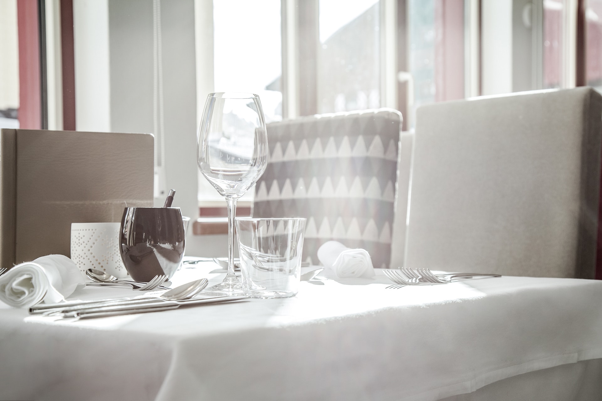 rigele-royal-restaurant-02 Elegantes Esszimmer mit makellosem Geschirr, das in natürliches Licht getaucht ist.