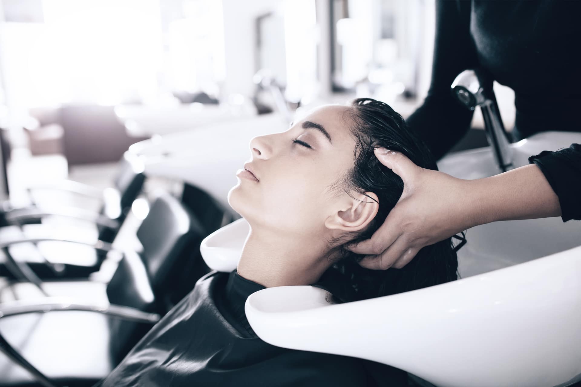 friseur Eine Frau entspannt sich beim Haarewaschen in einem Salon und erlebt einen Moment der Ruhe während ihrer Verwöhnsitzung.
